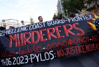 متظاهرون يرفعون لافتة خلال مظاهرة بعد حطام سفينة مهاجرين قاتلة قبالة اليونان ، في أثينا 