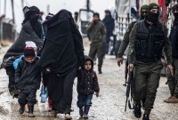 أطفال ونساء من عائلات مقاتلي "داعش" برفقة عنصر من "قسد" في مخيم الهول - AFP