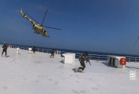 مروحية عسكرية تابعة للحوثيين تحلق فوق سفينة الشحن جالاكسي ليدر بينما يسير المقاتلون الحوثيون على سطح السفينة في البحر الأحمر