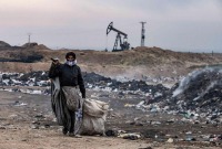 سوري يعمل بجمع القمامة قرب حقول للنفاط شمال شرقي سوريا - فرانس برس
