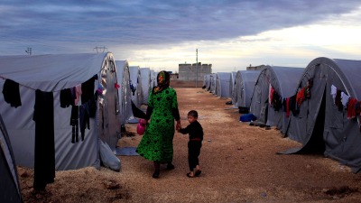 أم سورية تسير برفقة ابنها في مخيم بلدة سوروج على الحدود التركية السورية في ولاية شانلي أورفا التركية (Getty Images)
