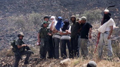 33 مستوطنون إسرائيليون ملثمون ويقف إلى جانبهم جنود من الجيش الإسرائيلي، الضفة الغربية المحتلة (الصحافة الإسرائيلية - فلاش 90)