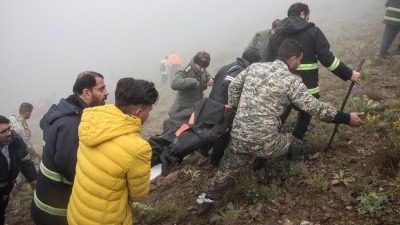 فرق الإنقاذ يحملون جثة الرئيس الإيراني إبراهيم رئيسي (رويترز)