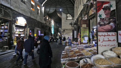 لافتة تحمل صورة رئيس النظام السوري بشار الأسد في سوق سوق البزورية بدمشق - AFP