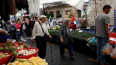 أشخاص يتسوقون في سوق لبيع المنتجات الطازجة في إسطنبول (رويترز)