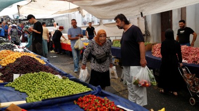 أشخاص يتسوقون في سوق لبيع المنتجات الطازجة في إسطنبول (رويترز)