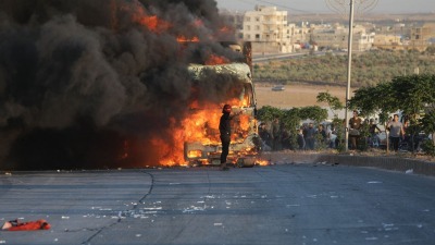 متظاهر يقف أمام شاحنة تركية مشتعلة خلال احتجاجات ضد تركيا في منطقة تسيطر عليها المعارضة السورية شمال حلب، سوريا، 1 يوليو 2024. (صورة وكالة فرانس برس)